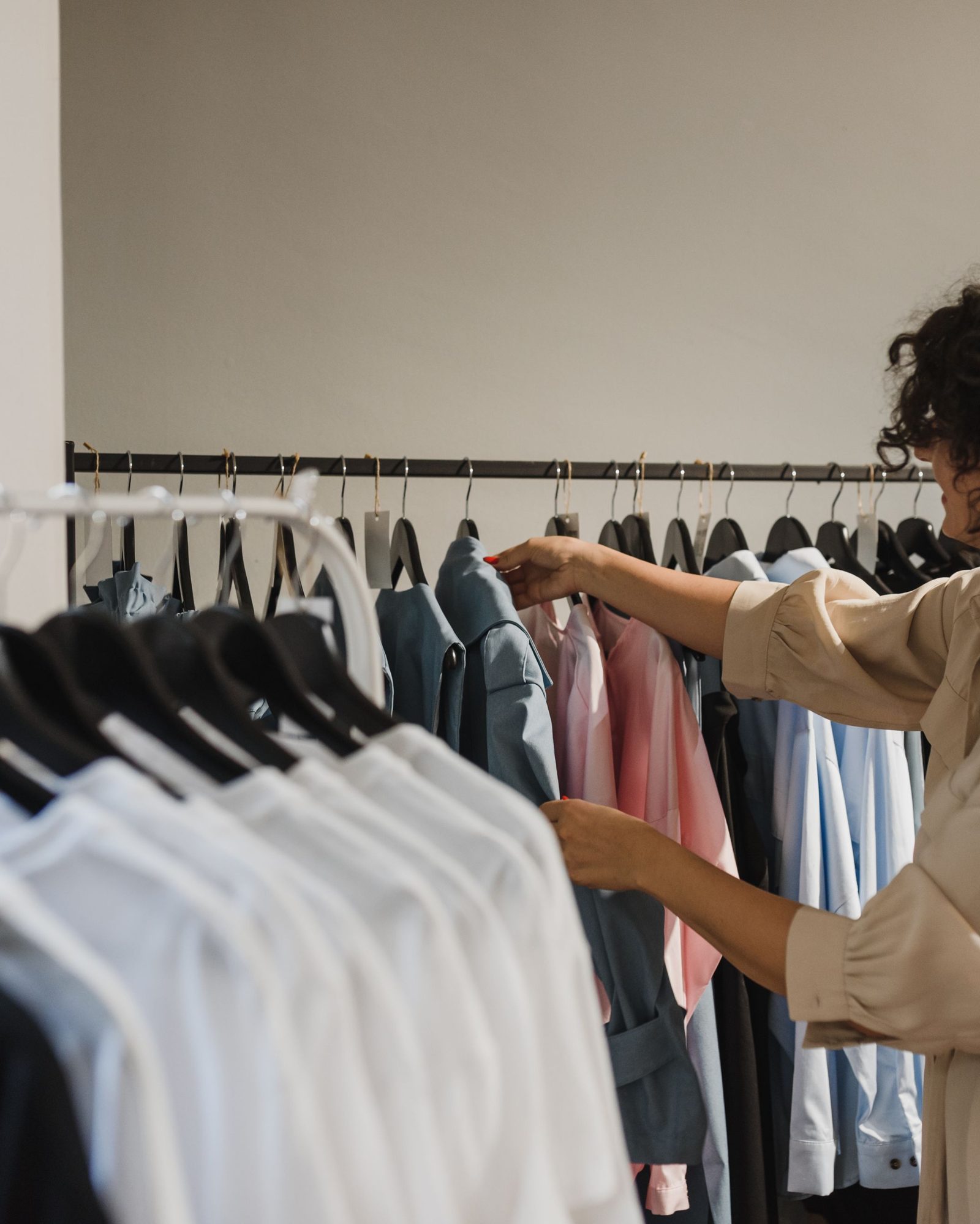 Une cliente choisit une pièce sur un portant, dans une boutique claire