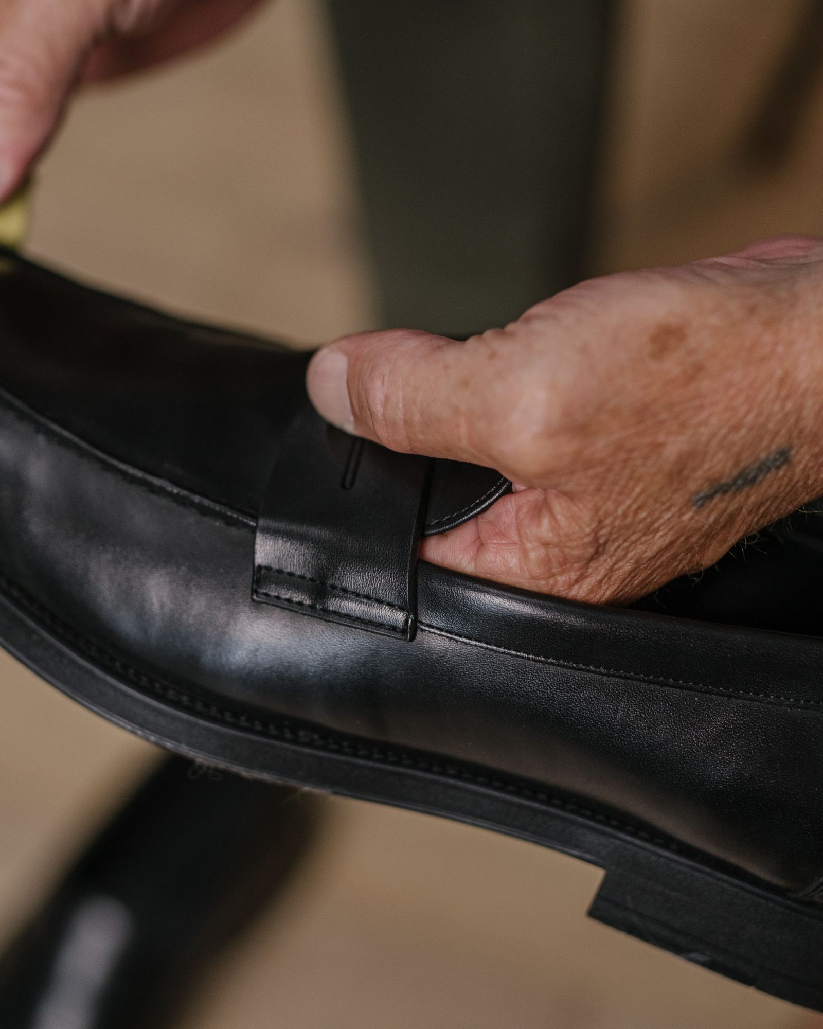Mains gantées appliquant une crème sur une chaussure en cuir noir